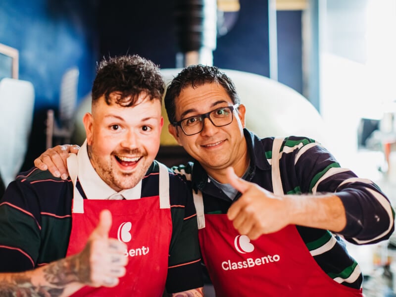 Two employees smiling with their arms around each other at a team bonding event